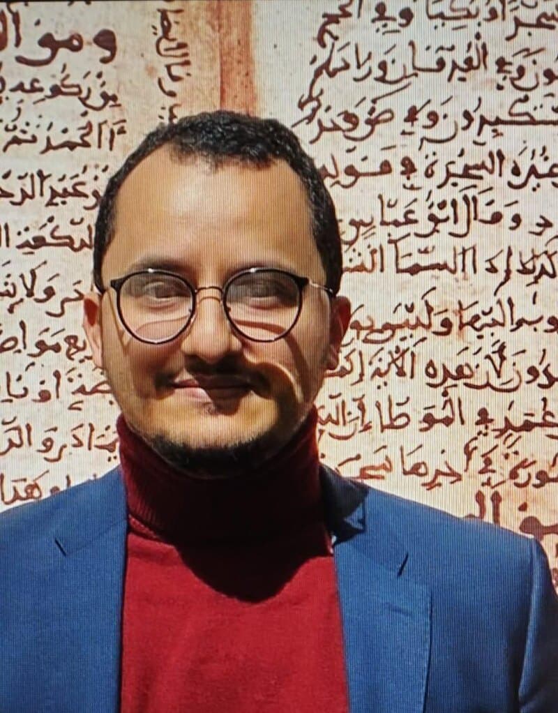 Portrait devant une page de manuscrit arabe agrandie.